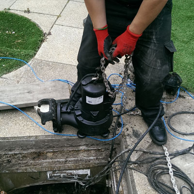 Man with pump near open drain